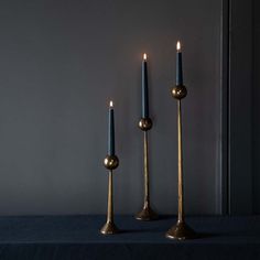 three candles are sitting next to each other on a blue tablecloth with a black background