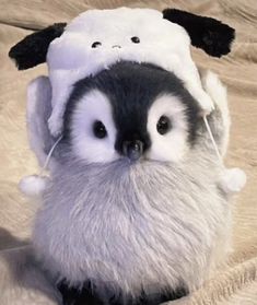 a small penguin with a stuffed animal on it's back and head in the shape of a sheep