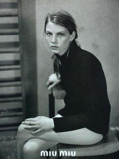 a black and white photo of a woman sitting on a stool