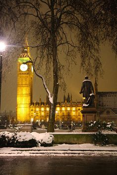 the big ben clock tower towering over the city of london covered in snow at night