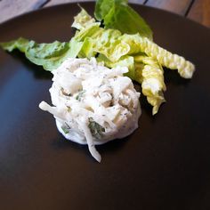 a black plate topped with salad and lettuce