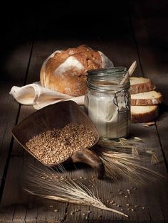 some bread and other food items on a wooden table with a glass jar filled with oatmeal