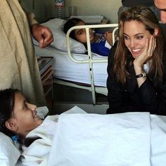 a woman sitting in a hospital bed next to two small children and an adult looking at her