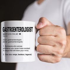 a person holding a white coffee mug with the words gastroentologist on it