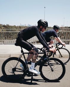 two bicyclists are riding down the street in front of each other on their bikes