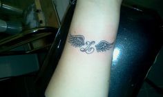 a woman's arm with an angel wing tattoo on the left side of her wrist