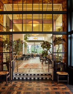 an open lobby with chairs and plants in the window sill, looking into the dining room