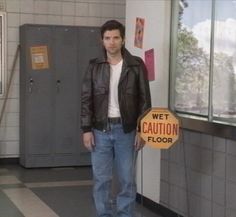 a man standing next to a caution sign in a room filled with lockers and cabinets