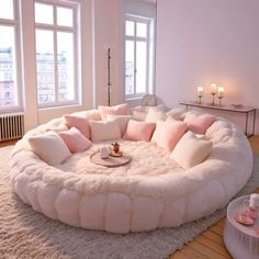 a living room filled with white furniture and lots of pillows on top of the floor