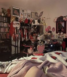 a bedroom with lots of clothes hanging on the wall and a bed covered in blankets