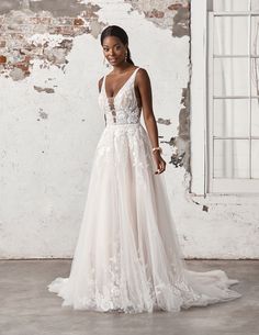 a woman standing in front of a brick wall wearing a wedding dress with an open back