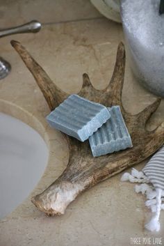 two soap bars sitting on top of a antler next to a sink