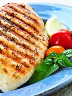 grilled chicken on a blue plate with tomatoes and basil