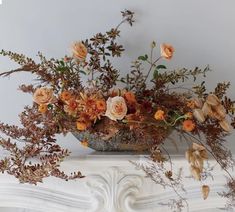 an arrangement of flowers in a vase on a mantle