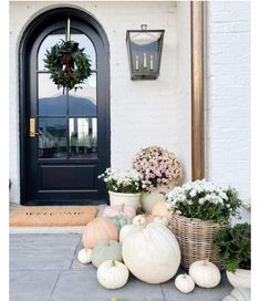 pumpkins and gourds on the front steps of a house with a wreath