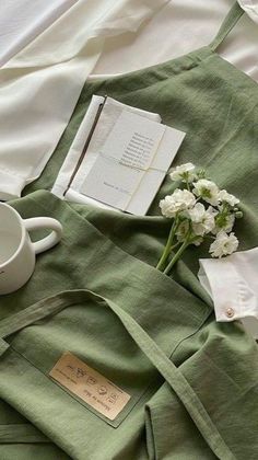 flowers and books are laid out on a bed with green linens, coffee cup, and napkins