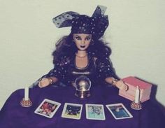 a doll sitting at a table with cards and candles on it's lap,