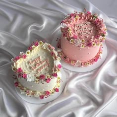 two birthday cakes with pink frosting and flowers on top, one is for a girl