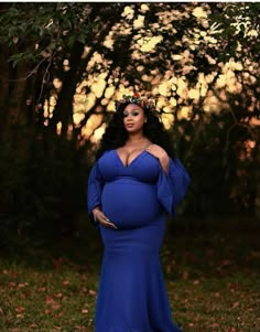 a pregnant woman in a blue gown poses for the camera with her hands on her hips