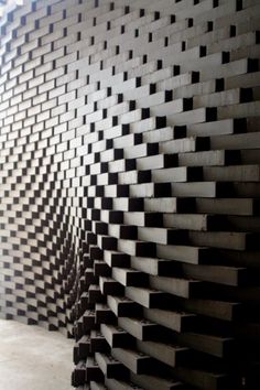 a wall made out of black and white squares in a room with concrete flooring