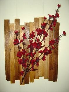 a bunch of red flowers sitting on top of a wooden wall mounted to the side of a fence