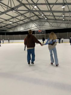 two people holding hands while skating on an ice rink