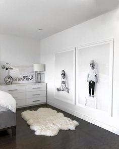 a bedroom with white walls and wood flooring, two framed pictures on the wall