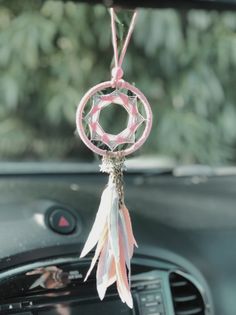 a car dashboard with a steering wheel hanging from it's center console, and a dream catcher attached to the dash board