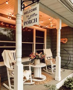 a porch with rocking chairs and a welcome sign on the front door, along with string lights