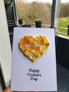 a hand holding up a card that says happy mother's day with buttons in the shape of a heart