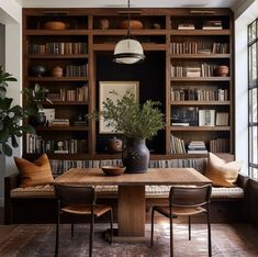 a dining room table and chairs with bookshelves in the background