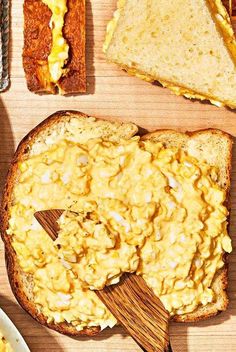 toasted bread with scrambled eggs on it and two serving spoons next to each other