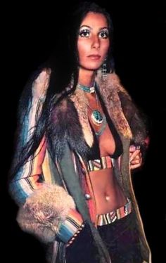 a woman in a fur coat posing for the camera with her hands on her hips