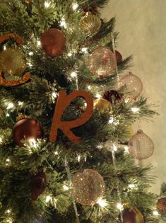 a christmas tree decorated with ornaments and the letter k on it's top is lit up