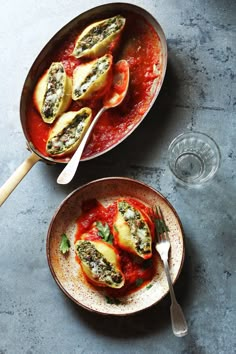 two bowls filled with stuffed shells covered in sauce and garnished with basil leaves