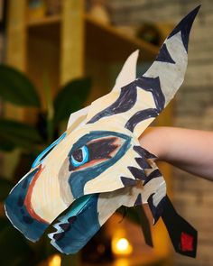 a hand holding a paper mache shaped like a tiger's head with blue eyes