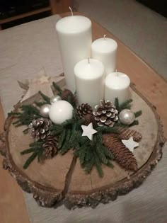 candles and pine cones are arranged on a wood slice