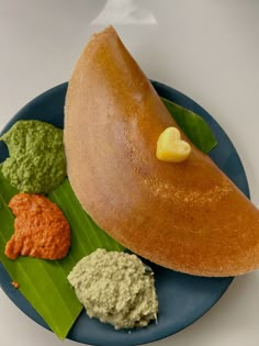 a blue plate topped with food on top of a leafy green plant next to sauces and condiments