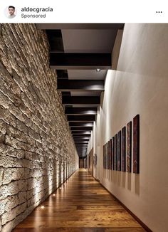 the hallway is lined with stone walls and wood flooring, along with pictures on the wall