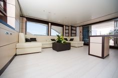 a living room filled with white furniture and large windows next to a bar area on top of a hard wood floor