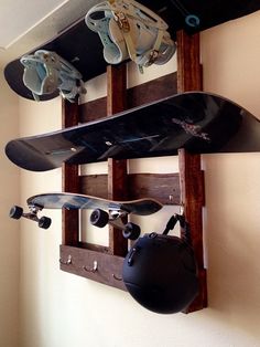 two skateboards mounted to a wall with helmets hanging on it's hooks,