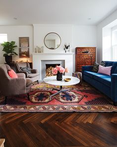 a living room with two couches and a rug on the floor in front of a fireplace