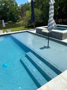 an empty swimming pool with steps leading up to it and an umbrella in the middle