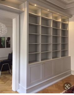 an empty bookcase in the middle of a room with hardwood floors and white walls