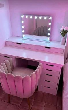 a pink vanity with lights on it and a chair in front of the mirror that is lit up