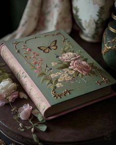 a green book with pink flowers and butterflies on it sitting on top of a table