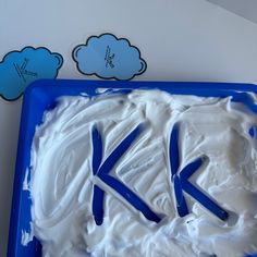 a cake with white frosting and blue icing in the shape of letters k