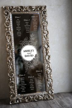 a silver framed mirror sitting on top of a wooden floor next to a white wall