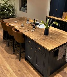 a kitchen island with four chairs and a bottle of wine on the counter in front of it