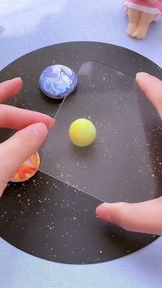 two hands are playing with plastic balls on a black tablecloth covered round surface, and one hand is reaching for the ball